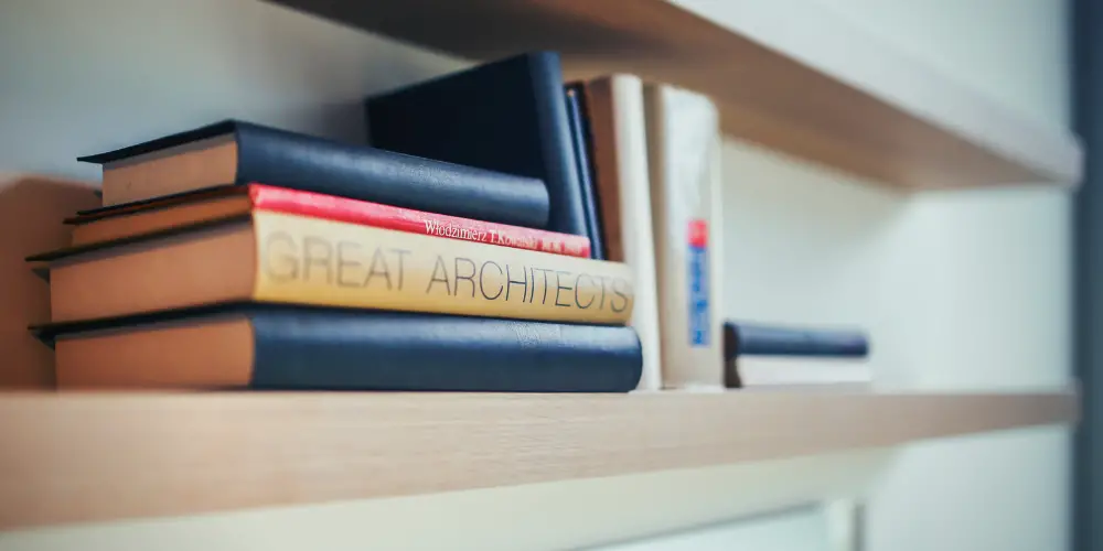 pile of books in a bookshelf mounted on the wall