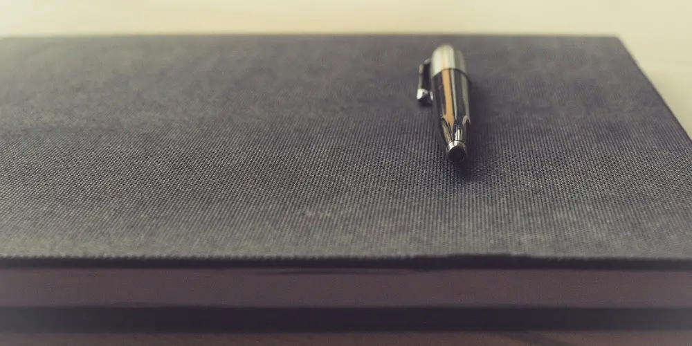 a pen at the top of a black notebook